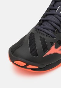 Pantofii sport negri, cu panouri din plasă și un logo portocaliu îndrăzneț. Material texturat cu un design elegant și vârf rotunjit.
