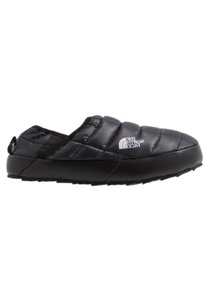 Chaussure noire isolée à enfiler avec tige matelassée, semelle en caoutchouc texturée et petite languette à l'arrière. Présente un logo sur le côté.