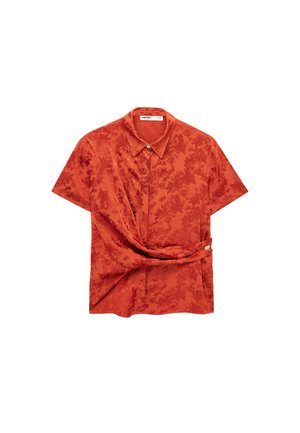Blouse en satin orange brûlé à manches courtes avec motif jacquard floral, détail torsadé à la taille et col avec boutons cachés.