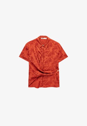 Blouse en satin orange brûlé à manches courtes avec motif jacquard floral, détail torsadé à la taille et col avec boutons cachés.