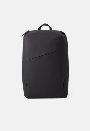 Czarny prostokątny plecak z gładkiej tkaniny, o minimalistycznym designie, z górnym zamkiem błyskawicznym i pojedynczą pętlą do noszenia na tle jednolitego białego tła.