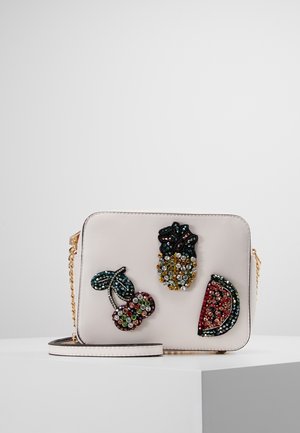 Kremowa torba na ramię z ozdobnymi naszywkami z koralików w kształcie wiśni, ananasa i arbuza oraz złotym łańcuszkiem na pasku.