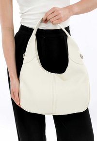 Borsa a tracolla in pelle bianca con forma hobo, superficie testurizzata, due manici curvi e dettagli di cucitura visibili lungo la cucitura frontale.