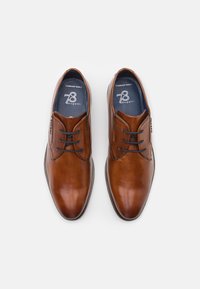 Zapatos de vestir de piel marrón con un acabado suave, forma de punta redondeada, diseño con cordones y agujetas azules en contraste. Suela de goma para un buen agarre.