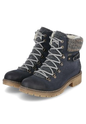 Bottes de randonnée bleu marine avec des poignets en feutre gris, des lacets gris, des accessoires en métal et des semelles en caoutchouc avec des motifs texturés.