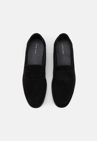 Mocassins en daim noir au toucher lisse, avec un accent cousu sur le devant et un bout légèrement arrondi. Intérieur étiqueté "Pier One."