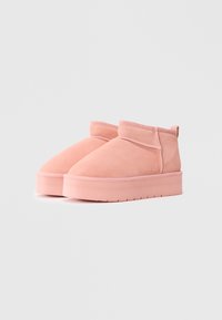 Krátke ružové semišové ankle boots s hrubými platformovými podrážkami a viditeľným šitím na bielom pozadí.