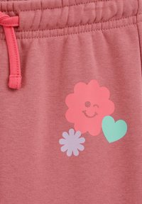 Lyserøde bomulds joggingbukser med snøre i taljen; har et legende motiv: en blinkende blomst og et hjerte i pastelfarver.