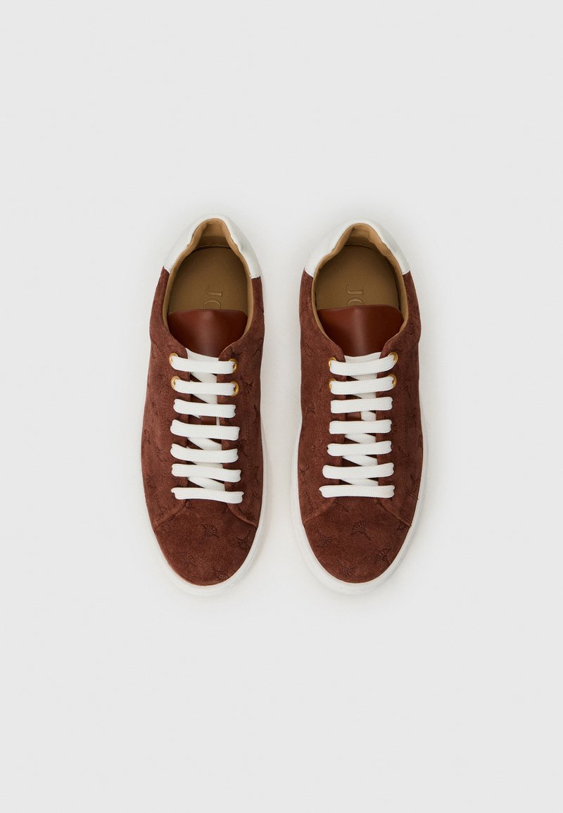 Braune Wildleder-Sneaker mit weißen Schnürsenkeln, goldenen Ösen und einem braunen Lederakzent an der Ferse. Gemusterte Oberfläche mit subtilen Designs.