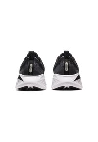 Scarpe sportive nere con una parte superiore in maglia testurizzata, dotate di un pull tab e una suola bianca angolare con accenti neri.
