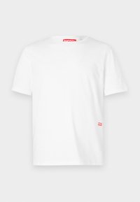Camiseta blanca de manga corta hecha de algodón, con cuello redondo y un pequeño logo rojo de Diesel cerca del dobladillo inferior en el lado izquierdo.