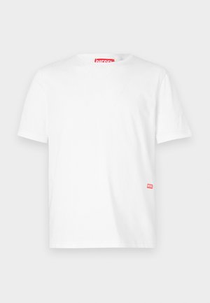 Bež majica s kratkimi rokavi iz bombaža, ki ima okroglo ovratnik in majhen rdeč logotip Diesel blizu spodnjega roba na levi strani.