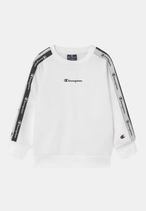 Hvid langærmet sweatshirt med sorte Champion-logoer på brystet og gentagne logoer på sorte og grå striber langs ærmerne.