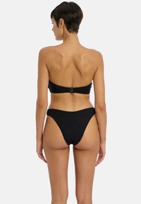 Černý bikinový set obsahující bandeau vršek s nastavitelným zapínáním na zádech a vysokými kalhotkami s texturovaným materiálem. Minimalistický design.