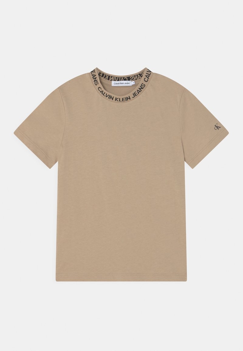 Camiseta de manga corta beige de Calvin Klein Jeans con cuello de marca y pequeño logo "CK" en la manga izquierda sobre fondo blanco.