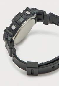 Μαύρο ψηφιακό ρολόι με ορθογώνιο πίσω μέρος από ανοξείδωτο ατσάλι, λουρί από υφασμένο καουτσούκ και πολλαπλά κουμπιά λειτουργιών στη πλευρά.
