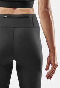 Legging noirs taille haute avec motif en diamant texturé, dotés d'une poche arrière zippée discrète et de coutures à plat pour plus de confort.