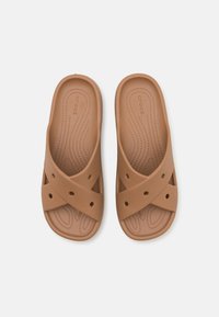 Sandales en caoutchouc marron avec une semelle intérieure texturée, un design à brides croisées et des accents perforés pour la respirabilité.