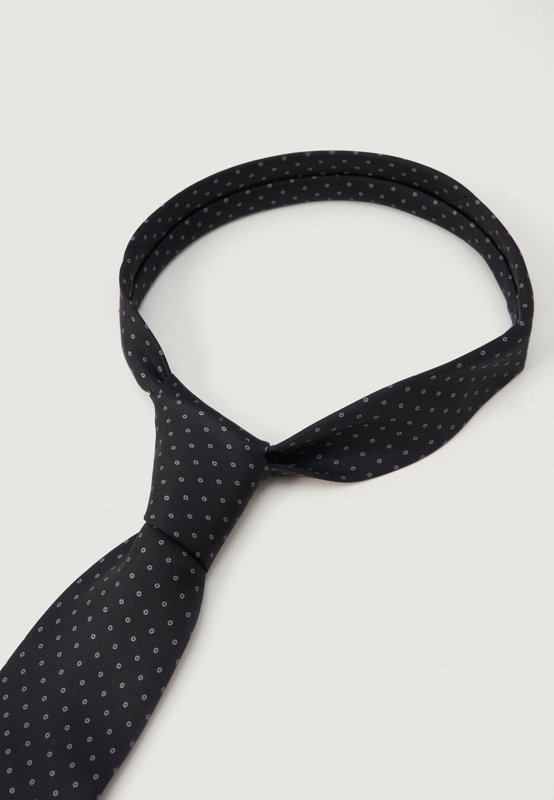 Schwarze Krawatte mit einem kleinen grauen Punktmuster, klassisch gebunden, auf einem schlichten hellen Hintergrund präsentiert.