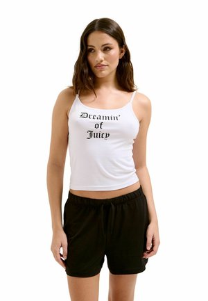 Weißes Baumwoll-Tanktop mit schwarzer Schrift "Dreamin' of Juicy" und dünnen Trägern, kombiniert mit schwarzen Shorts mit elastischem Bund.