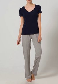 Tamsiai mėlynas trumpomis rankovėmis marškinėliai su apvalia iškirpte, derinami su šviesiai pilkomis kelnėmis. Abu pagaminti iš minkštos medžiagos, laisvo silueto ir minimaliais detalėmis.