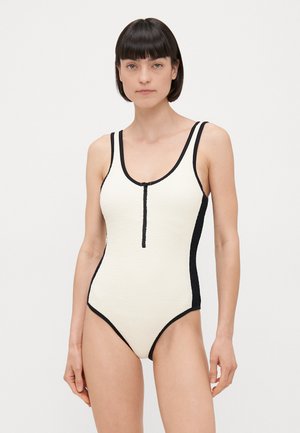 White textured one-piece swimsuit with black accents, featuring a front zip closure and double straps on the shoulders.