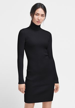 Schwarzes, geripptes Strickkleid mit taillierter Silhouette, langen Ärmeln und hohem Rollkragen. Glatte Textur, endet über dem Oberschenkel.
