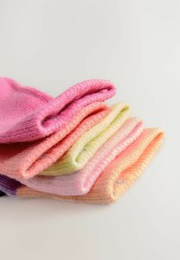 Colorful socks stacked in gradient shades of pink, peach, and cream. Each pair is knitted, featuring soft, textured fabric with rolled cuffs.
