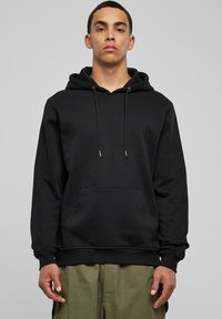 Sudadera negra con un bolsillo canguro frontal, capucha con cordón, puños acanalados y dobladillo. Hecha de un tejido suave que presenta una textura lisa.