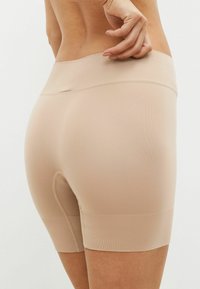 Bodysuit-stijl shorts van gladde, rekbare nude stof met een hoge tailleband en een kleine opening aan de achterkant. Naadloos ontwerp voor comfort.