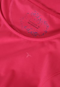 Top sportivo fucsia luminoso con scollatura rotonda, caratterizzato da un design grafico blu con testo e un accento logo sul tessuto.