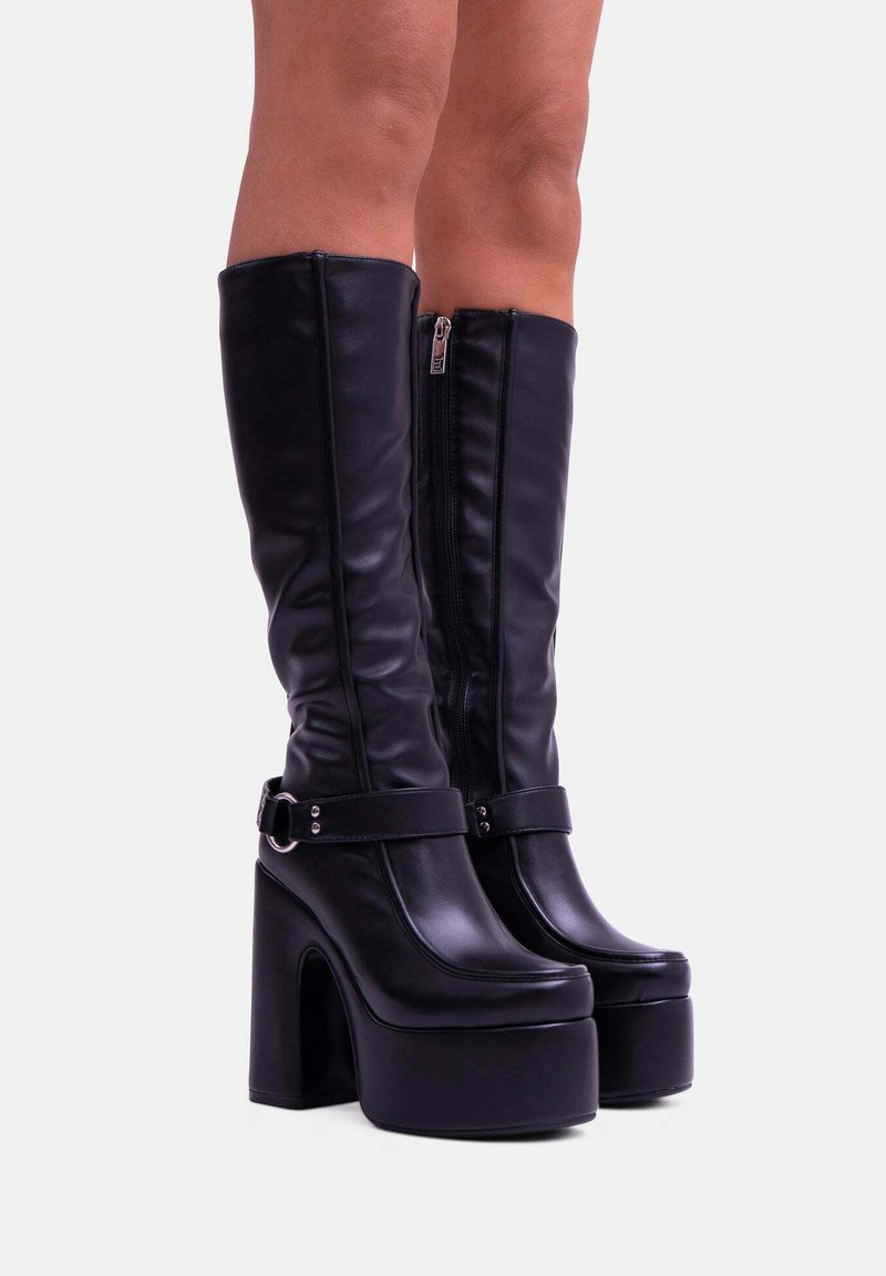 Stivali neri alti fino al ginocchio con piattaforma, realizzati in pelle liscia, dotati di una cerniera laterale, ampie cinture con accessori in argento e un spesso tacco a blocco.