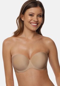 Beige strapless beha met gladde, gevormde cups en een naadloos ontwerp, met een zachte textuur en gebogen randen voor comfort.