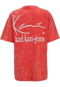Red, short-sleeve T-shirt with a textured, faded design. Features white text reading "Kani" and "karl kani-jeans" on the back.