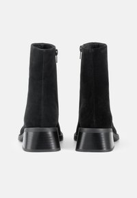 Sorte nubuck ankelstøvler med rund tå og sort stablet hæl. Udstyret med en sidelukning for nem påtagning og en glat overflade.