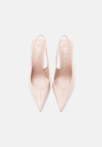 Escarpins slingback vegan beige avec bout pointu, finition brillante et design ajouré sur les côtés. Doublure intérieure lisse.