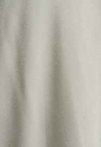 Helles graues Gewebe mit einer glatten, dicht gewebten Textur und subtilen vertikalen Falten, die sanfte Schatten erzeugen.