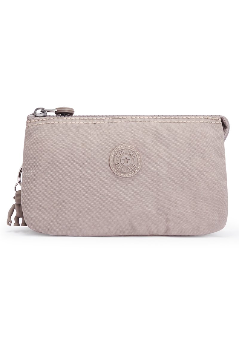 Lichtbeige ritstas gemaakt van duurzaam materiaal, met een ronde logo patch en een klein decoratief figuurtje aan de ritssluiting.