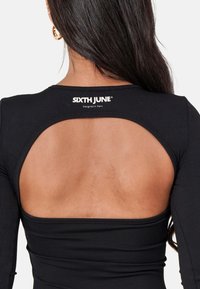 Haut noir côtelé à manches longues et dos en scoop. Présente le logo "SIXTH JUNE" au niveau du col et une texture lisse.