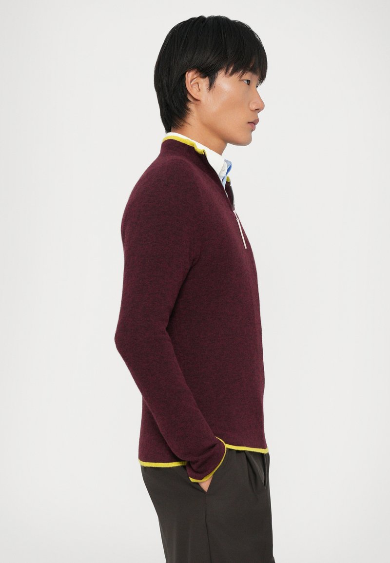 Bordeaux gebreide pullover met gele accenten bij de kraag en de zoom, voorzien van een ritskraag en een slim fit silhouet.