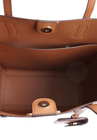 Interno di una borsa a tracolla in pelle marrone con una superficie liscia, una chiusura a scatto magnetica e dettagli cuciti. Presenta tasche laterali per l'organizzazione.