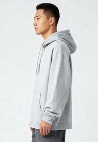 Felpa grigia con cappuccio realizzata in tessuto morbido, dotata di una grande tasca frontale, polsini a coste e una vestibilità comoda.