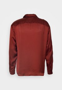 Camicia a maniche lunghe in raso color ruggine con una trama liscia. Presenta un colletto appuntito e polsini con bottoni. Design semplice sul retro.