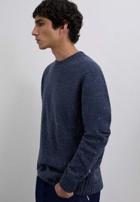 Suéter azul marino con textura moteada, cuello redondo y puños y dobladillo acanalados. La tela parece suave y cálida, adecuada para un uso casual.