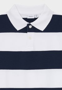Polo a righe navy e bianche in cotone, con colletto classico, due bottoni e un'etichetta con la scritta "name it" all'interno del colletto.