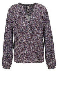 Bloem blouse met lange mouwen, een V-hals en knoopsluiting aan de voorkant. Voornamelijk donkerblauw met rode en lichtblauwe bloemenpatronen op een crèmekleurige achtergrond.