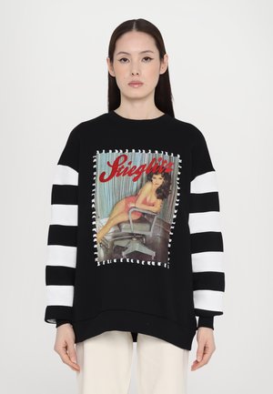 Black sweatshirt with striped white sleeves, featuring a graphic print of a seated figure against a striped backdrop, outlined with contrasting stitching.