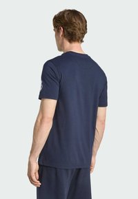 Camiseta de algodón de color azul marino con mangas cortas y cuello redondo, con un acento de logo en la manga izquierda y una textura suave.