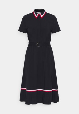Czarna sukienka z krótkim rękawem, z paskiem w talii, czerwono-białym paskowanym kołnierzykiem i wykończeniem na dole, spódnica o kroju A sięgająca kolan.