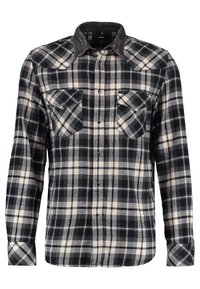 Chemise à carreaux noire et blanche à manches longues avec deux poches poitrine devant et un col foncé.